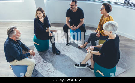 Business Team im Kreis sitzen und Diskutieren im Büro. Gruppe von Menschen in einer Lektion auf Team building sitzen. Stockfoto