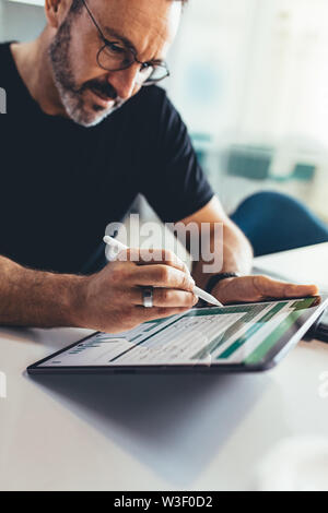 Geschäftsmanns, der auf digitalen Tablet mit einem Stift. Männliche Unternehmer Überprüfung weniger finanzielle Berichte über seinem Tablet Computer. Stockfoto