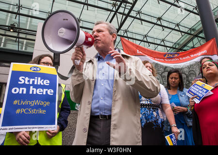 London, Großbritannien. 15. Juli, 2019. Mark Serwotka, Generalsekretär der Public and Commercial Services Union (PCS), Adressen, Catering- und Reinigungspersonal ausgelagert im Ministerium für Wirtschaft, Energie und industrielle Strategie Expositionsindizes (BEI) über Fremdfirmen ISS und Aramark auf den Streikposten außerhalb der Regierung Abteilung zu arbeiten, nachdem man einen unbefristeten Streik für die London existenzsichernde Löhne und Bedingungen vergleichbar mit der Beamte sie arbeiten neben und ein Ende des Outsourcing. Credit: Mark Kerrison/Alamy leben Nachrichten Stockfoto