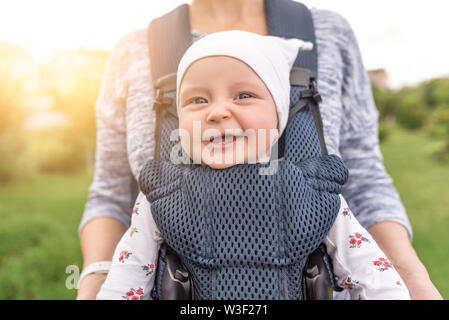 Die junge Mutter und ihr Baby in der Babytrage. Stockfoto