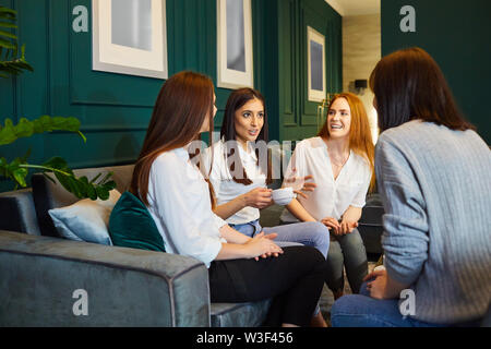 Junge Inhalt Frauen sitzen auf einem Sofa zu Hause in Kaffee und plaudern in der Freizeit Stockfoto