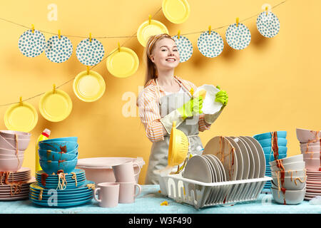 Aktive Maid in Handschuhen und grauen Schürze Holding eine Platte und ein Blick in die Kamera. nach oben Foto schliessen. hygienekonzept. Stockfoto