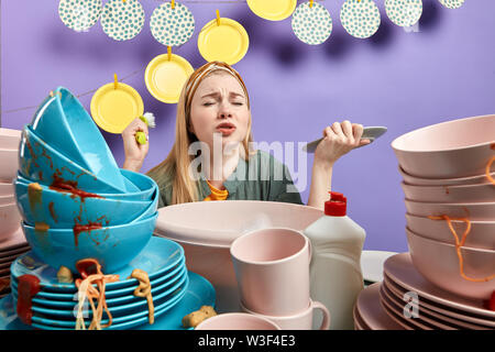 Müde Frau mit geschlossenen Augen überfordert mit Waschmaschine dreckiges Geschirr in der Küche ausgestattet. Bis portrait schließen. Stockfoto