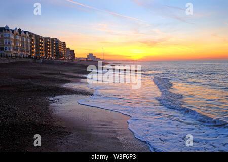 Brighton Beach und das Meer bei Sonnenuntergang, die Sonne ist orange und tief am Himmel hinter den Brighton Pier Casting eine orange Glühen am Himmel, th Einstellung Stockfoto