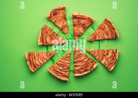 Apfelkuchen in Stücke geschnitten auf grünem Papier Hintergrund. Über Aussicht auf leckere American Pie. Teile der hausgemachten Herbst Dessert. Süßes Gebäck los Flach Stockfoto