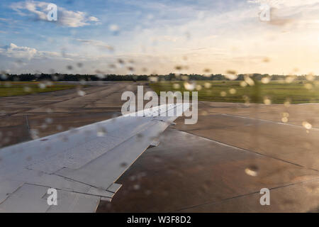 Flugzeugflügel von Embraer 140, Regentropfen auf dem Flugzeug Fenster und Sonnenlicht vor dem Start am internationalen Flughafen Gulfport Biloxi, Mississippi, USA. Stockfoto