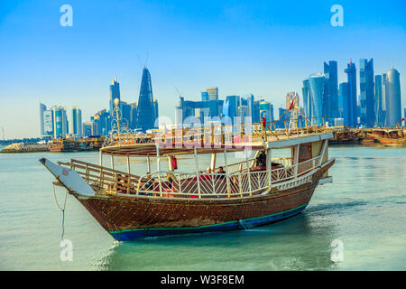 Doha, Katar - Februar 23, 2019: die Menschen Touristen auf einer Dhow und die Küste von Doha West Bay Skyline mit Qatar International Exhibition Centre, Doha Turm Stockfoto