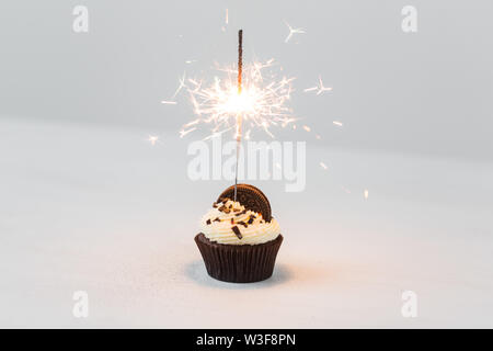 Essen, Party und Urlaub Konzept - Geburtstag Cupcake mit Wunderkerzen auf weißem Hintergrund Stockfoto