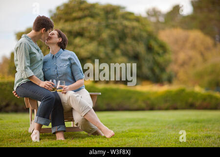 Mitte nach paar sitzt auf einem Stuhl und Küssen. Stockfoto