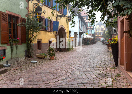 Malerische Gasse das Reiseziel Riquewihr, Dorf der elsässischen Weinstraße, Frankreich, Kopfsteinpflaster Lane, Rebe und Blumenschmuck, Herbst Szene Stockfoto