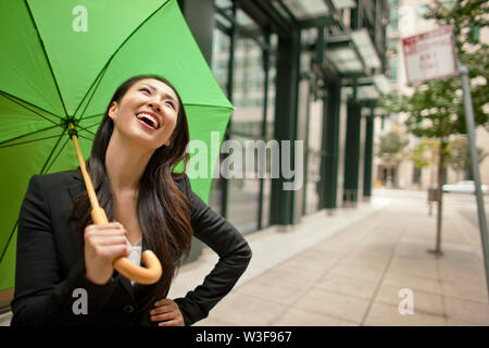 Junge Geschäftsfrau lachend, während man mit der Hand auf ihre Hüfte. Stockfoto