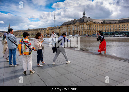 Japanische Touristen fotografieren, Place de la Bourse. Die neuen Brunnen Miroir d'Eau, Wasser spiegeln. Bordeaux, Gironde. Region Aquitanien. Frankreich Europa Stockfoto