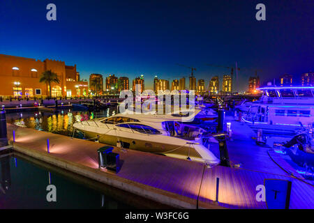 Doha, Katar - Februar 18, 2019: Luxuriöse Yachten und Boote in Porto Arabien Marina in der Nacht. Die Pearl-Qatar in Doha künstliche Insel und ein beliebtes Stockfoto