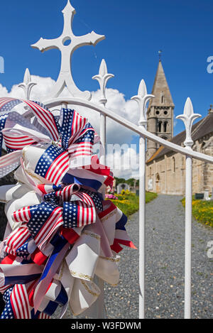 Die amerikanische Band zu Zaun der Kirche Notre-Dame de l'Assomption angebracht zu erinnern, ww2 im Dorf Colleville-sur-Mer, Calvados, Normandie, Frankreich Stockfoto