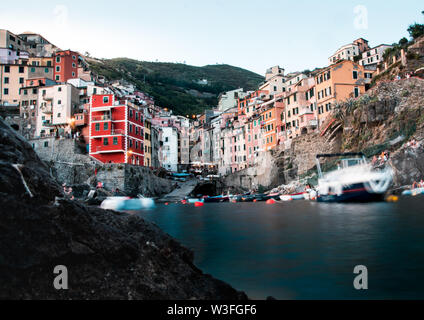 Eine der fünf Länder Städte Riomaggiore von einem niedrigen Winkel am Wasser als lange Belichtung fotografiert. Stockfoto