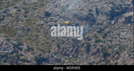 Palma de Mallorca/Spanien - Juli 9, 2019: Feuerwehrmann Hubschrauber während seiner Wok ein Feuer um die Sa Calobra Berge zu löschen. Stockfoto