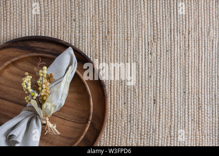 Ort, Einstellung auf Glasgewebe Hintergrund mit zwei gestapelten Holzplatten und Bettwäsche Serviette mit gelben Beeren serviette Ring Stockfoto