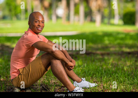 Foto von einem gutaussehenden Jungen afrikanischen amerikanischen Mann im Park sitzen. Stockfoto