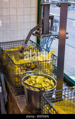 Pommes Frites potato Schneidemaschine, große Handbuch Kartoffel Cutter, Hobel. Der Prozess der Vorbereitung für das Kochen von Pommes frites, geschnitten in Scheiben geschnittene Kartoffel in Einem Stockfoto