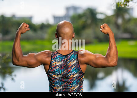 Ansicht der Rückseite Porträt einer starken macho Mann seine Arme biegen. Park See Szene im Hintergrund Stockfoto