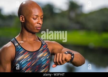 Porträt einer African American fitness Modell an seiner Smartwatch suchen Stockfoto