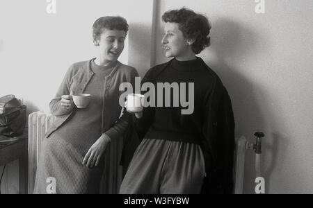 1950, historische, zwei Lehrerinnen das Tragen der Kleidung des EFR, lange Röcke, wolle Strickjacken, einer Tasse Tee und einem zusammen plaudern, England, UK. Stockfoto