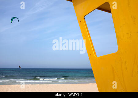 Ein Kitesurfer auf dem Meer hinter einem Rettungsschwimmer Lookout, Corralejo, Fuerteventura Stockfoto