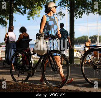 Junge Frau im Sommer Tücher zu Fuß mit dem Fahrrad entlang der Küste Merihaka während Kallio Block Party 2018 in Helsinki, Finnland Stockfoto