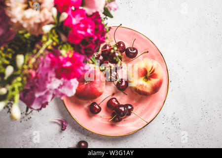 Schöne rosa essen Hintergrund. Blumen und Beeren auf einem rosa Platte. Sommer essen Hintergrund. Stockfoto