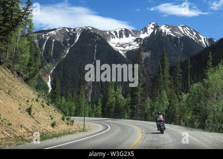 Motorradfahrer in der amerikanischen Flagge Lederjacke, Reiten in Colorado Rocky Mountains schneebedeckten Gipfel Stockfoto