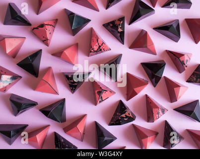 Dunkle Schokolade Pralinen auf rosa Hintergrund, schwarz und Korallen. Stockfoto