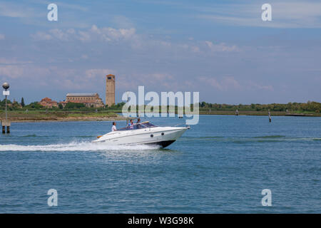 Weiß Schnellboot Beschleunigung von Torcello, einer kleinen Insel in der Lagune von Venedig, Italien: Blick auf die Kathedrale Santa Maria Assunta, Santa Fosca und Campanile Stockfoto