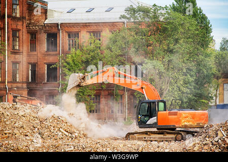 Orange Bagger arbeiten auf den Ruinen einer zerstörten Gebäude. Reinigung der Schutt, Gebäudeabbruch und Clearing Website Thema Bild Stockfoto