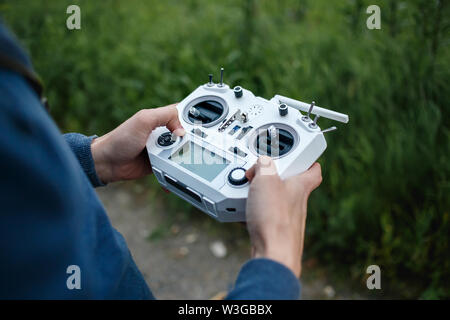 Fernbedienung für quadrocopter, close-up. Sender für Steuern bewegen Gerät in männlichen Händen, unscharfer Natur Hintergrund. Elektronik, Hobby, aeromodeling Konzept. Custom Made. Stockfoto