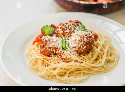 Spaghetti Nudeln mit Hackfleischbällchen in Tomatensauce, Käse über sie fallen Stockfoto