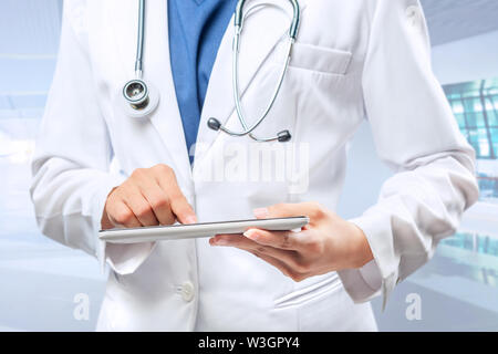 Frau Doktor im weißen Kittel und Stethoskop mit Tablette am Krankenhaus Stockfoto