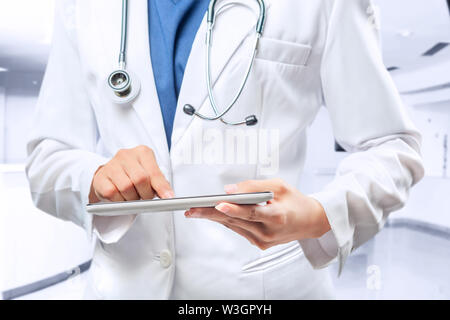 Frau Doktor im weißen Kittel und Stethoskop mit Tablette am Krankenhaus Stockfoto