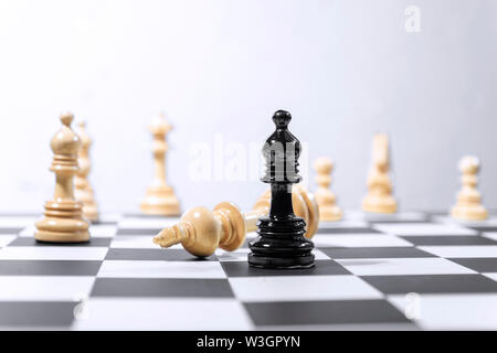 Holz- König Schachfigur besiegt durch schwarze Bischof Schachfigur auf dem Schachbrett Stockfoto