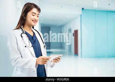Asiatische Frau Arzt im weißen Kittel und Stethoskop mit Tablette am Krankenhaus Stockfoto