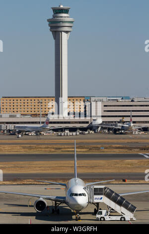 Ein All Nippon Airways (ANA) Boeing 757-Linienflugzeug wird vor dem Kontrollturm am Haneda Airport, Tokio, Japan, gewartet. Stockfoto