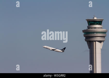 Ein All Nippon Airways (ANA) Boeing 737-800-Linienflugzeug, in Star Alliance-Lackierung, hinter dem Flugsicherungsturm am Haneda Airport, Tokio, Japan Stockfoto