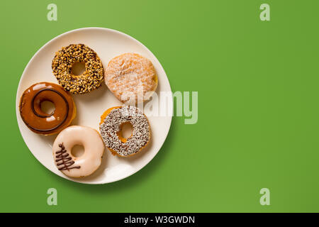 Donuts auf der Platte mit grünem Hintergrund und kopieren Sie Platz für Text-food Konzept Bild. Stockfoto