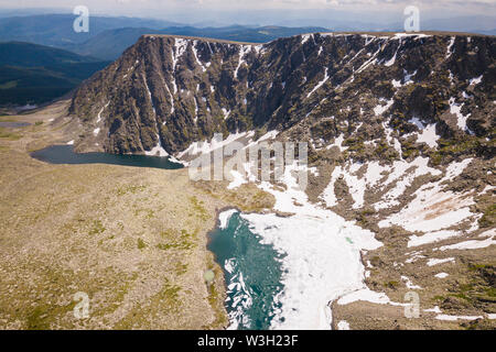 Ultra Wide Panorama der Horizont. Berge bedeckt mit Schnee, blauer See, Lichtung mit einem grünen Nadelwald gegen den blauen Himmel. Tolle Aussicht auf Stockfoto