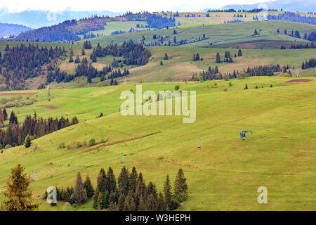 Die Aussicht von der Höhe der Frühling Landschaft der Karpaten und der blauen Masten der Seilbahn auf den Gipfel des Berges. Stockfoto