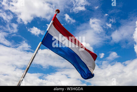 Niederlande Flagge. Niederländische nationale Symbol winken auf der Pole gegen den blauen Himmel mit Wolken, sonnigen Tag Stockfoto