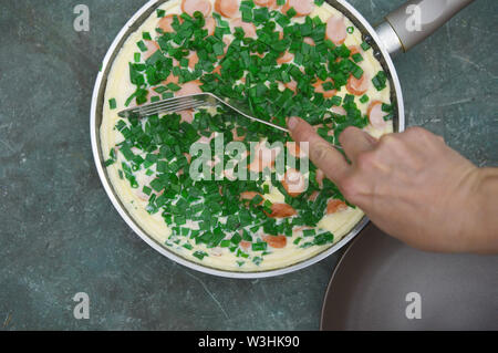 Vor Aufnahme einer Hand mit Gabel Verkostung der scrambbled Eier mit Wurst und Zwiebeln Stockfoto