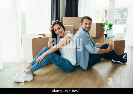 Junges Paar sitzt in der Nähe von Kartons, Umzug neues Haus Stockfoto