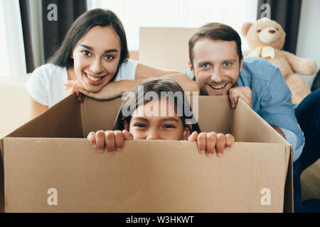 Glückliches Paar Kisten auspacken und Spaß mit Tochter im Wohnzimmer im neuen Zuhause Stockfoto