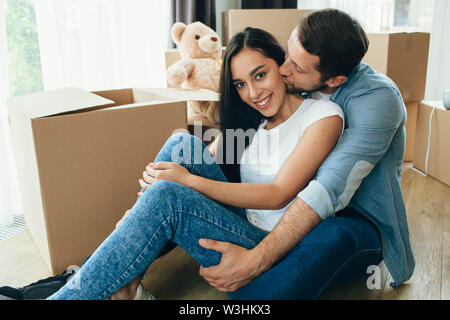 Junges Paar sitzt in der Nähe von Kartons, Umzug neues Haus Stockfoto