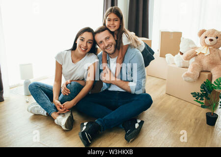 Glückliches Paar mit Kind beim Sitzen am Boden, im neuen Haus Stockfoto